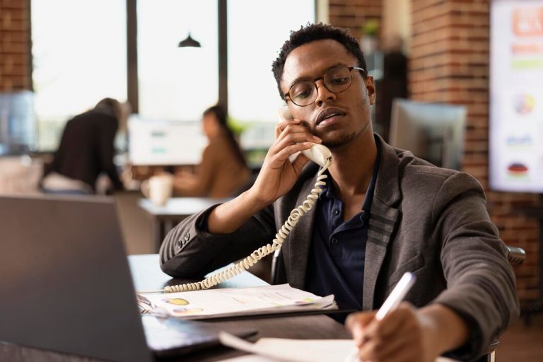 Le directeur écrit des notes pendant l'appel téléphonique.