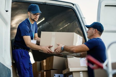 Des livreurs chargent des boîtes de carton dans une fourgonnette pendant qu'ils se préparent à l'expédition.